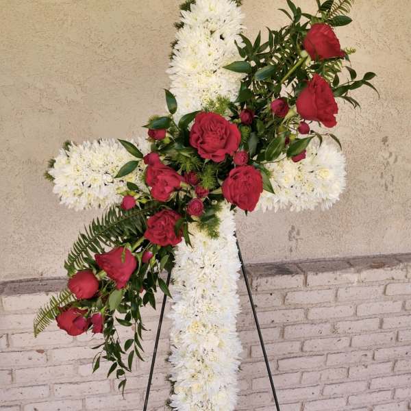 Tall standing white cross arrangement with red roses on a metal easel