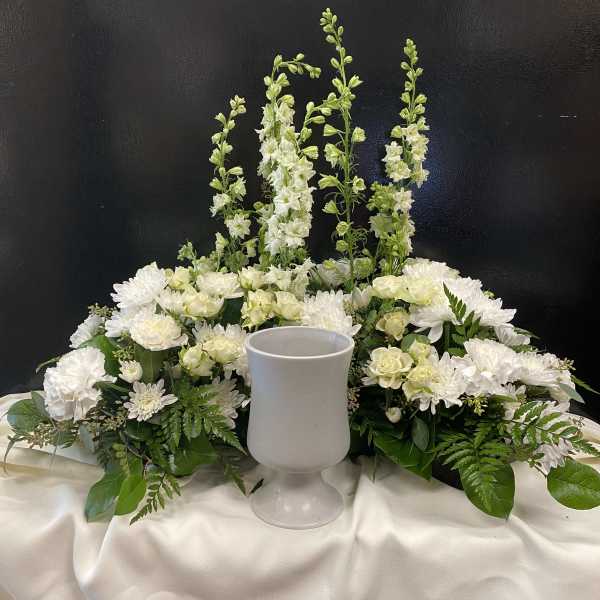 White floral centerpiece with a goblet vase on a draped table