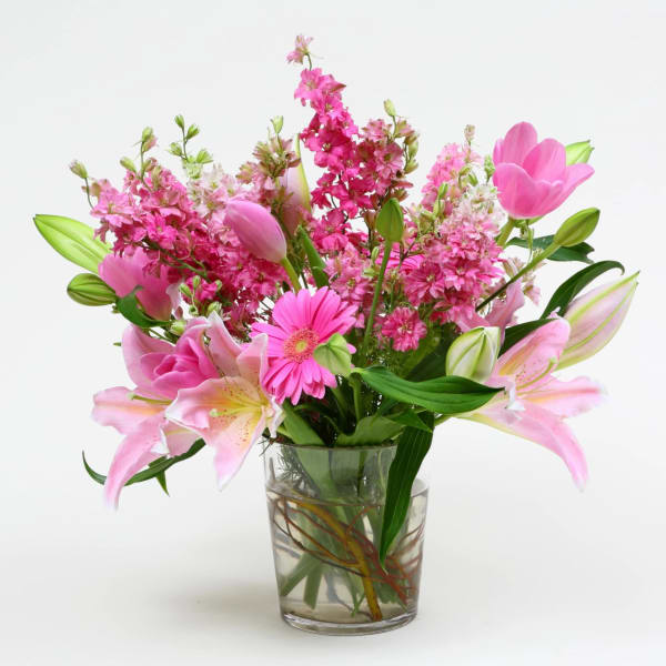 Pink lilies, tulips, and gerbera daisies in a glass vase