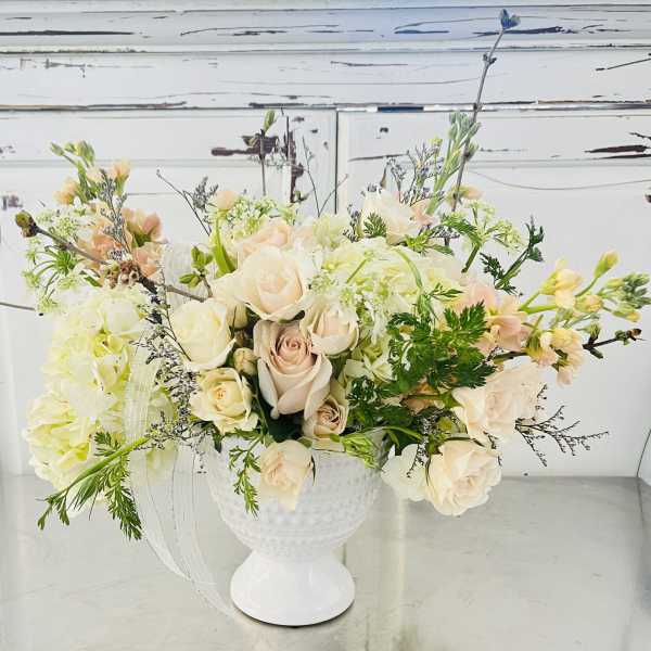 Cream and blush roses arranged in a white vase