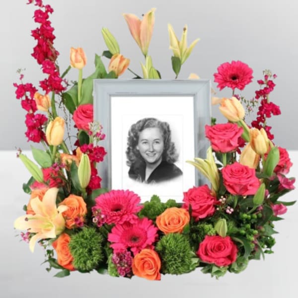 Framed black-and-white portrait surrounded by pink, orange, and yellow flowers