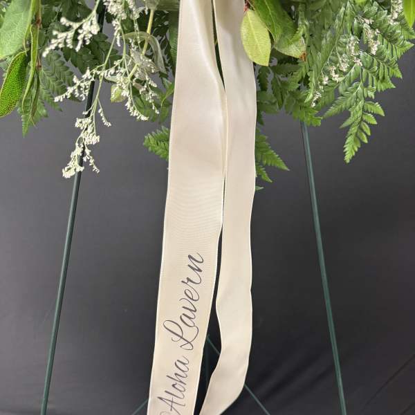 Green floral wreath with a cream ribbon reading "Aloha Lauren"