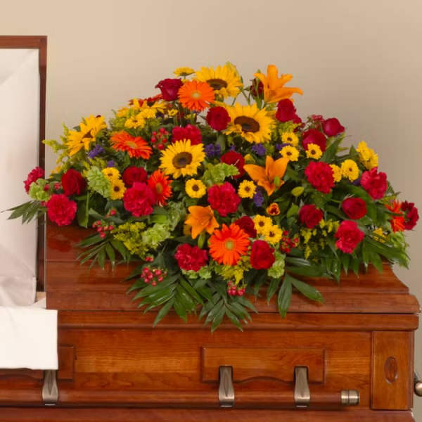 Bright mixed flower spray on a wooden casket