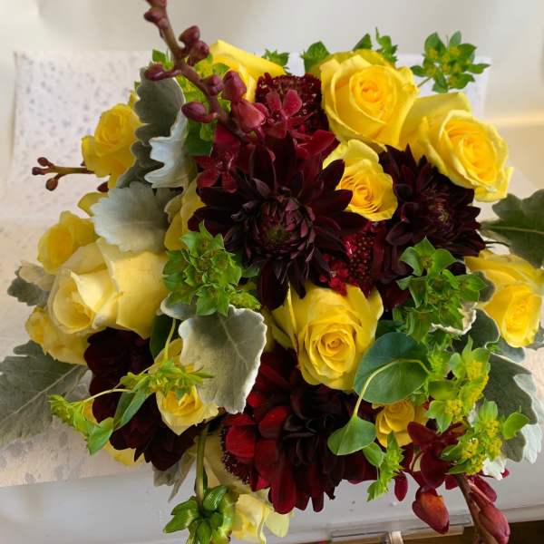 Bouquet of yellow roses and dark burgundy dahlias with silvery foliage
