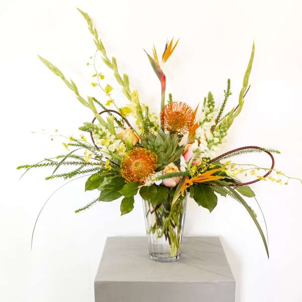 Tropical floral arrangement in a clear glass vase with orange blooms