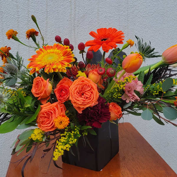 Orange and yellow floral arrangement in a black vase