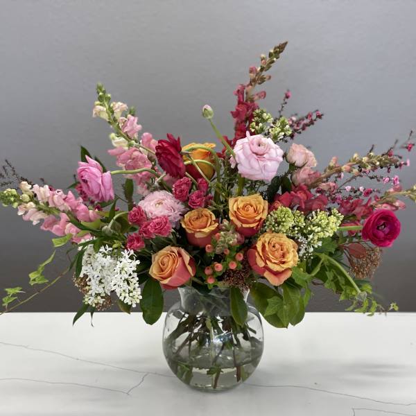 Mixed bouquet of pink and orange flowers in a clear glass vase