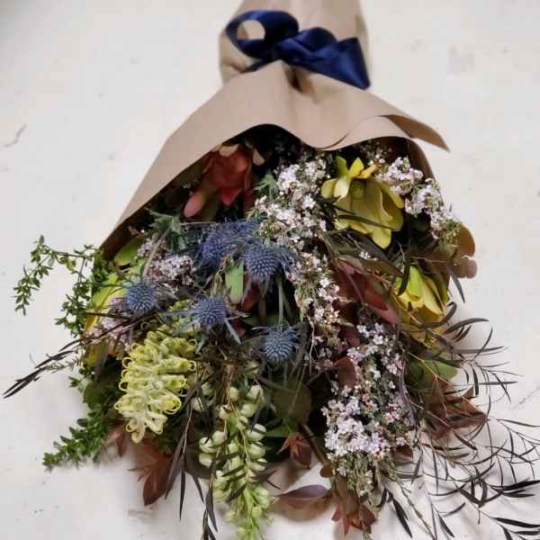 Mixed bouquet wrapped in brown paper with a navy ribbon
