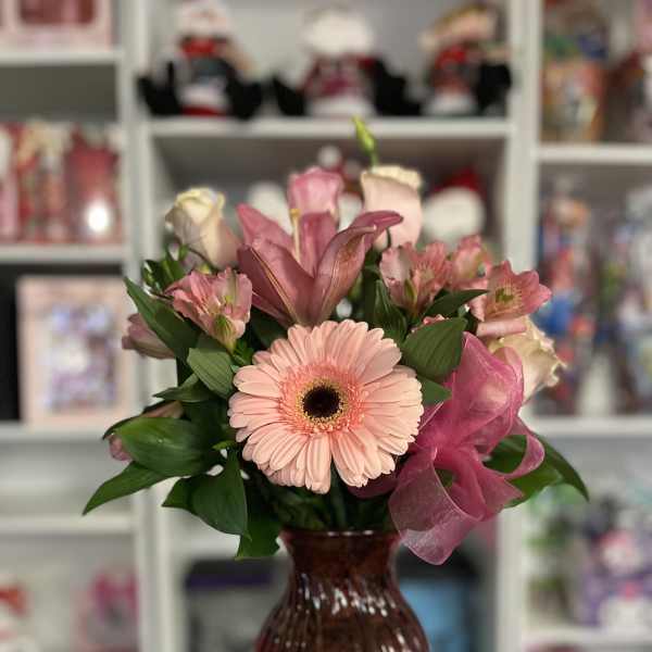 Pink gerbera bouquet in a red glass vase with a sheer ribbon
