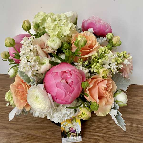 Bouquet of pink, peach, and white flowers in a low arrangement