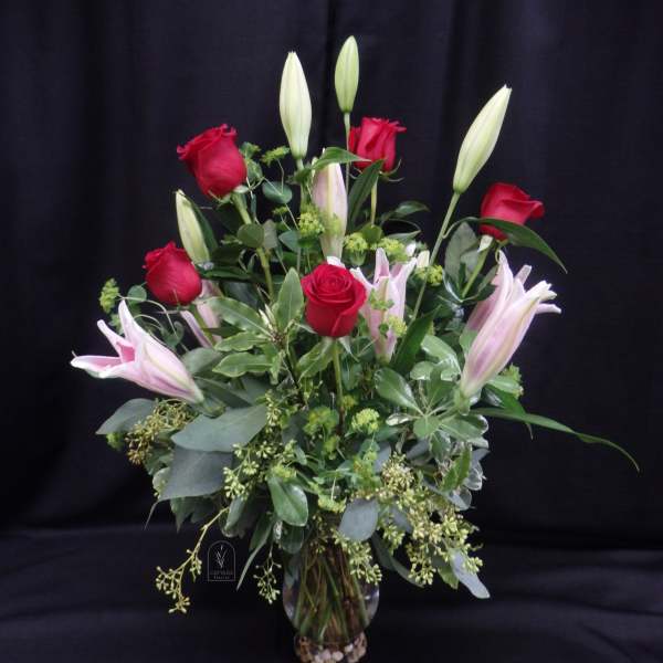 Bouquet of red roses and pink lilies in a glass vase