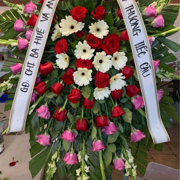 Large funeral wreath of red and pink roses with white daisies and ribbons