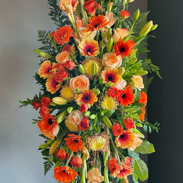 Tall standing floral spray with orange and peach blooms on an easel