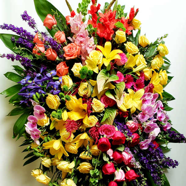 Large mixed floral standing spray with roses, lilies, orchids, and purple accents