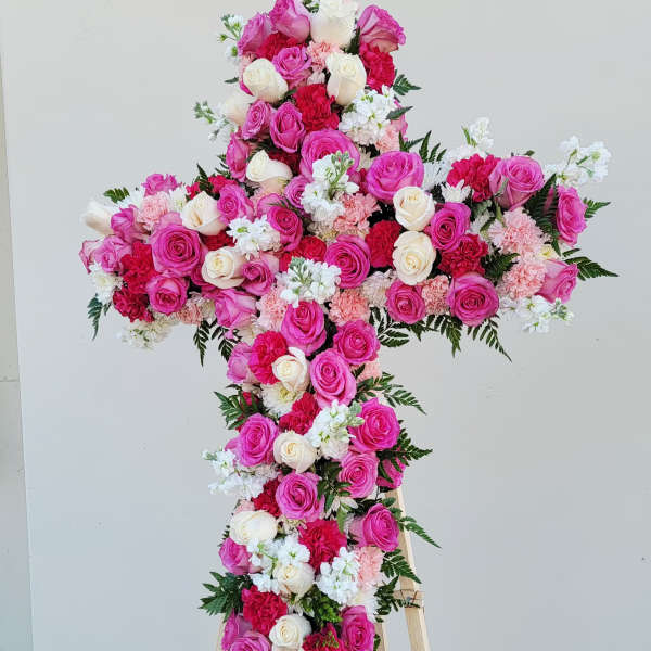 Cross-shaped floral arrangement of pink and white roses on a stand