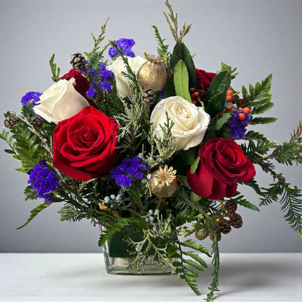 Bouquet of red and white roses in a glass vase with pinecones and gold ornaments