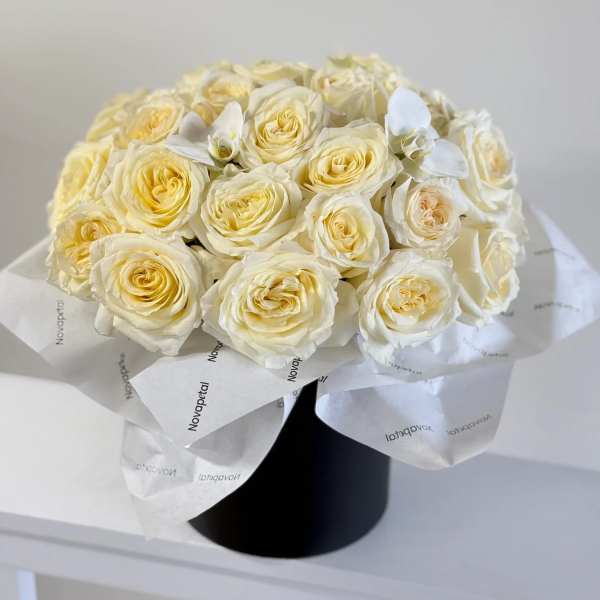 Bouquet of cream roses wrapped in white paper in a black box