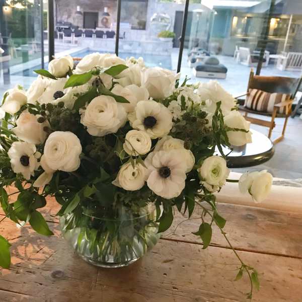 White floral arrangement in a clear glass vase on a wooden table