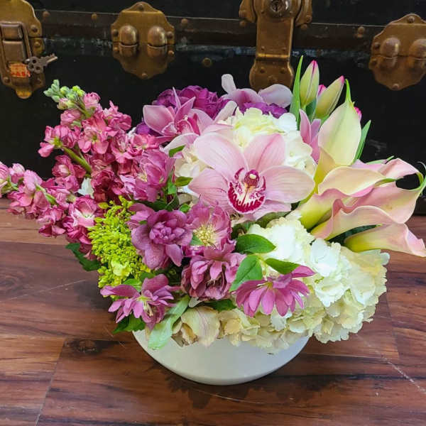Pink and white mixed flower arrangement in a white bowl vase
