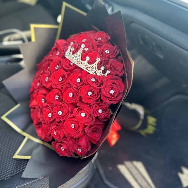 Bouquet of red roses with a jeweled crown topper in black wrap