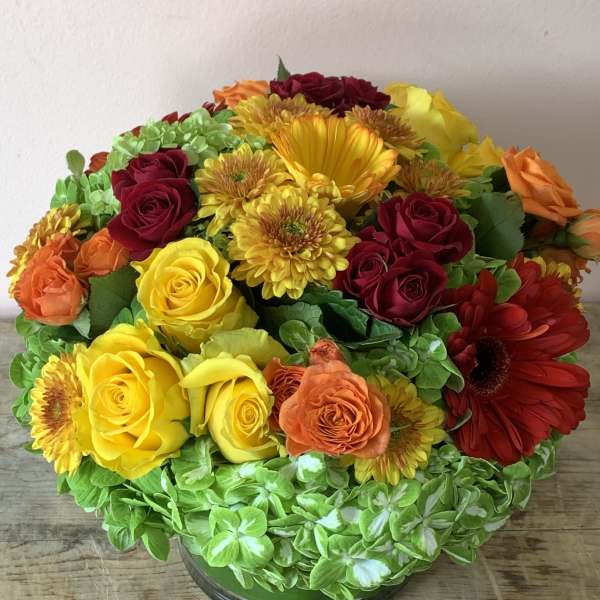 Mixed bouquet of roses, gerbera daisies, and chrysanthemums in a glass vase