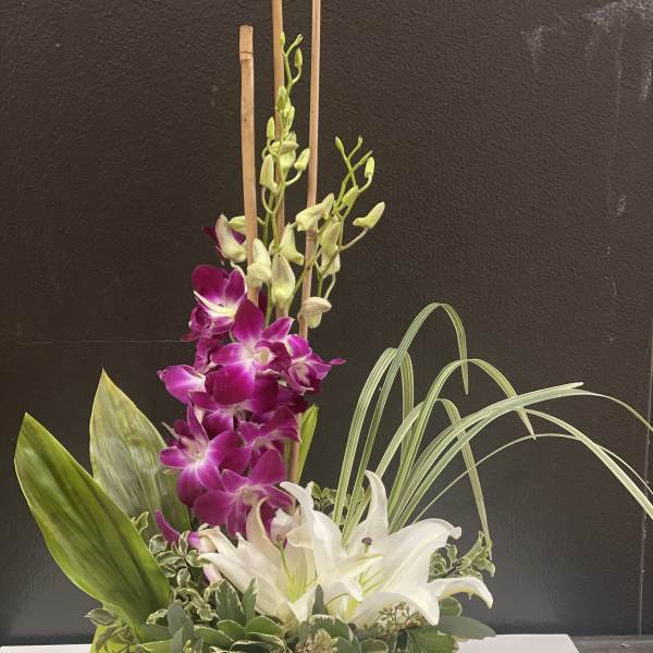 Purple and white orchids arranged in a low green container