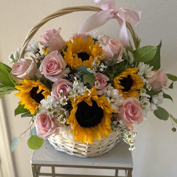 Basket arrangement of pink roses and sunflowers with a pink ribbon