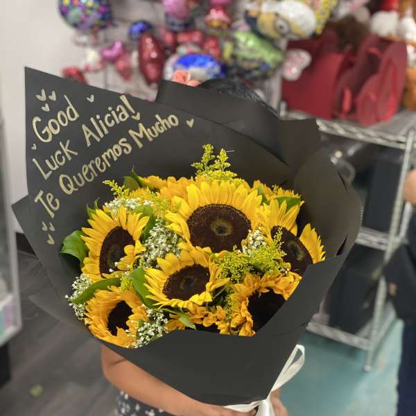 Bouquet of yellow sunflowers wrapped in black paper with a white ribbon