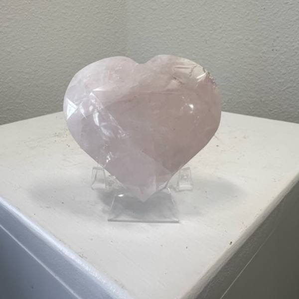 Pale pink heart-shaped crystal on a clear stand