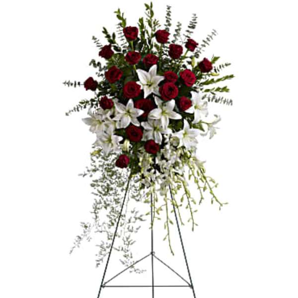 Standing floral spray of red roses and white lilies on an easel