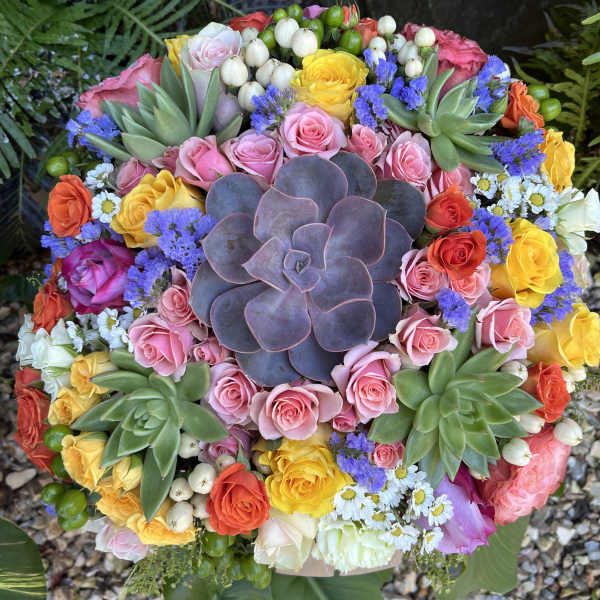 Round bouquet with pink and yellow roses and a large purple succulent center