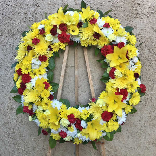 Circular wreath of yellow, red, and white flowers on a wooden easel