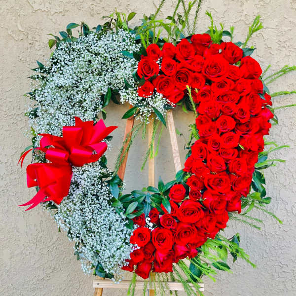 Heart-shaped red rose wreath with white baby's breath and a red bow