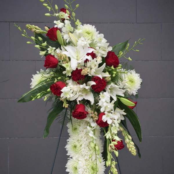 Standing floral spray with red and white flowers on a black easel
