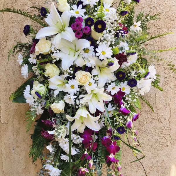 Large standing floral spray with white lilies, daisies, and purple accents