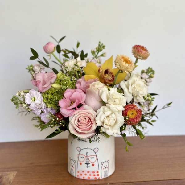 Mixed bouquet of pink, white, and yellow flowers in a decorated ceramic vase