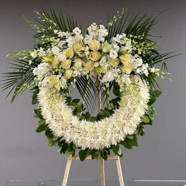 Large white floral wreath on a wooden stand