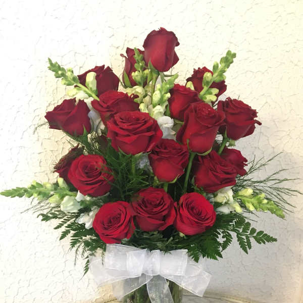 Bouquet of red roses in a glass vase with a white ribbon