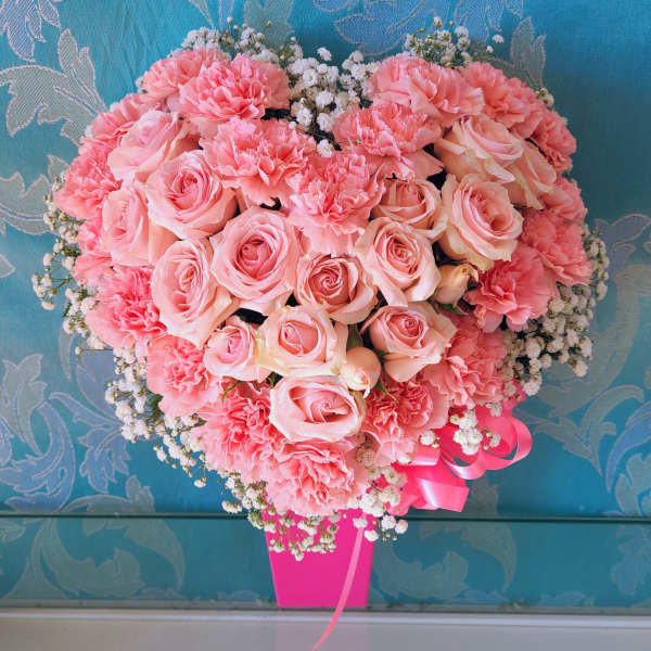 Heart-shaped bouquet of pink roses and carnations with baby's breath