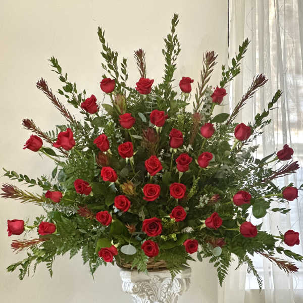 Large arrangement of red roses in a decorative pedestal vase