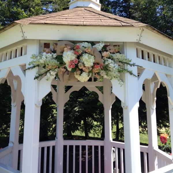 Floral arrangement of white and pink blooms on a white gazebo