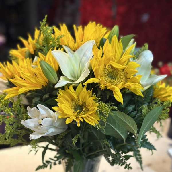 Yellow sunflowers and white lilies in a glass vase