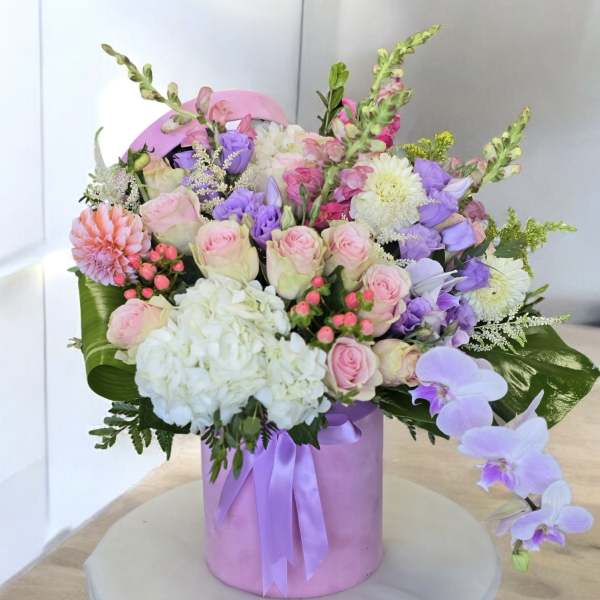 Pink and lavender bouquet in a round pink box with ribbon