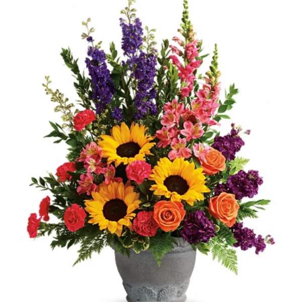 Colorful mixed bouquet in a gray vase with sunflowers, roses, and tall purple blooms
