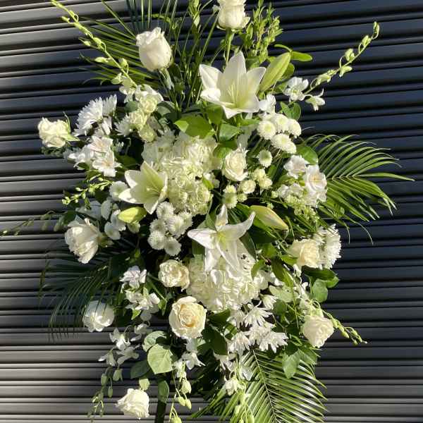 Tall white floral standing spray with lilies and roses on easel