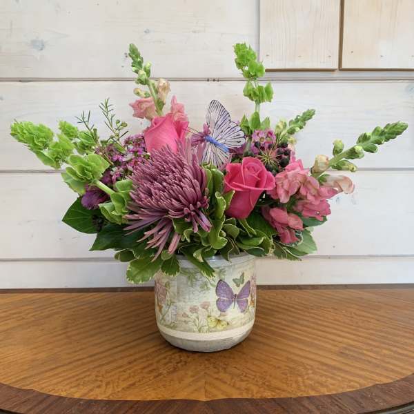 Pink and purple floral arrangement in a butterfly-decorated vase