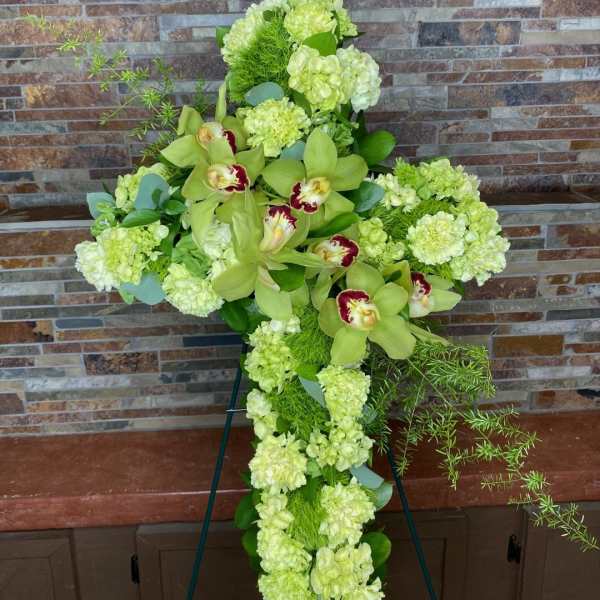 Green floral cross with orchids and pale blooms on an easel