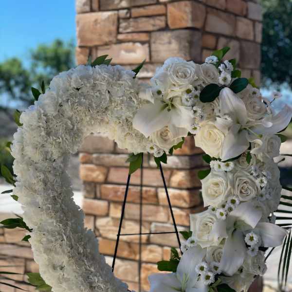 White floral heart wreath with roses and lilies on an easel