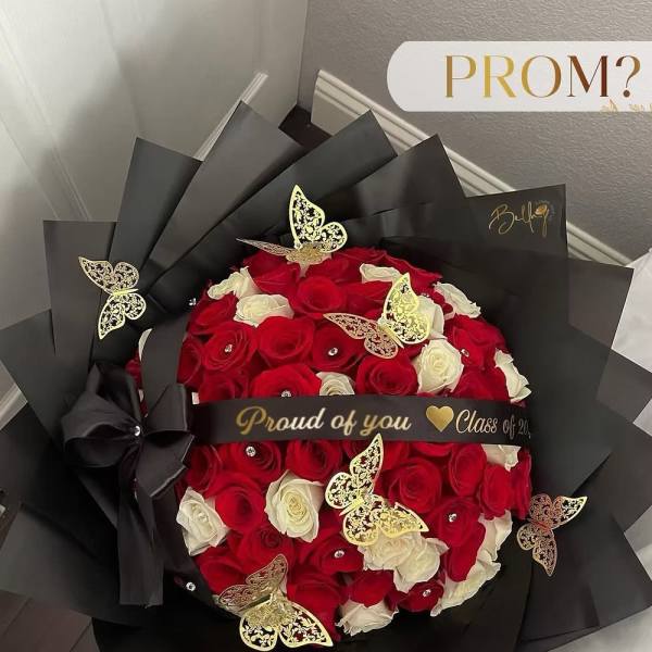 Bouquet of red and white roses wrapped in black paper with gold butterfly accents