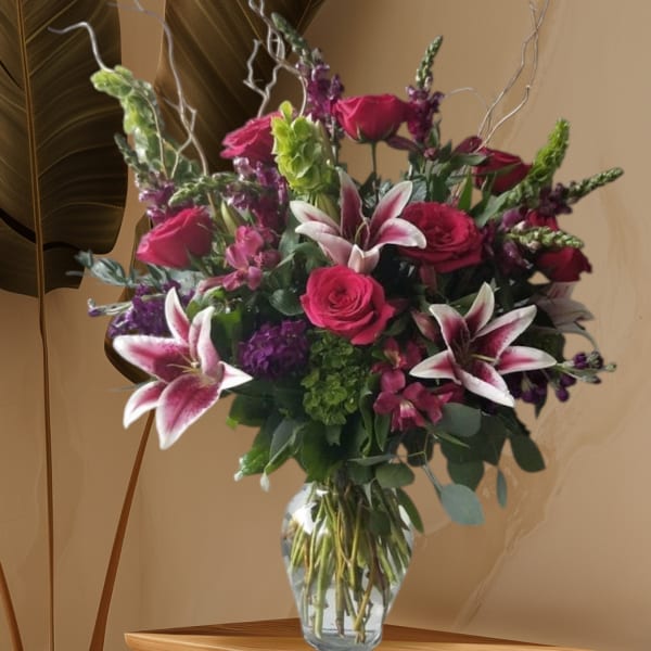 Pink roses and lilies arranged in a clear glass vase